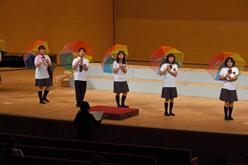 傘を手に歌う子どもたち