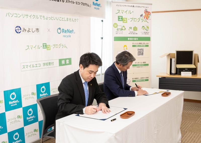 協定書に署名する黒田代表取締役会長と小山市長